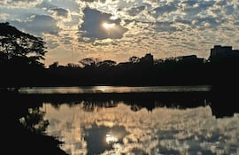 Paisaje con lago reflejando el cielo nublado y árboles alrededor, generando un ambiente de tranquilidad.
