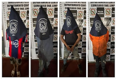 Cuatro personas con capuchas en comisaría, una viste camiseta naranja, otra gris, y una más lleva prendas en rojo y azul.
