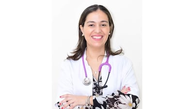 Dra. Irene Benítez sonriente, con bata blanca y estetoscopio púrpura, en fondo blanco.