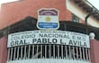 Fachada del Colegio Nacional Pablo L. Ávila con cartel en primer plano, en un ambiente exterior tranquilo.