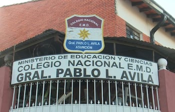 Fachada del Colegio Nacional Pablo L. Ávila con cartel en primer plano, en un ambiente exterior tranquilo.