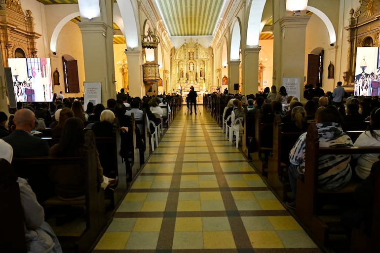 Multitud de asistentes en la Catedral de Asunción, muchos de pie y sentados, prestando atención al altar decorado.