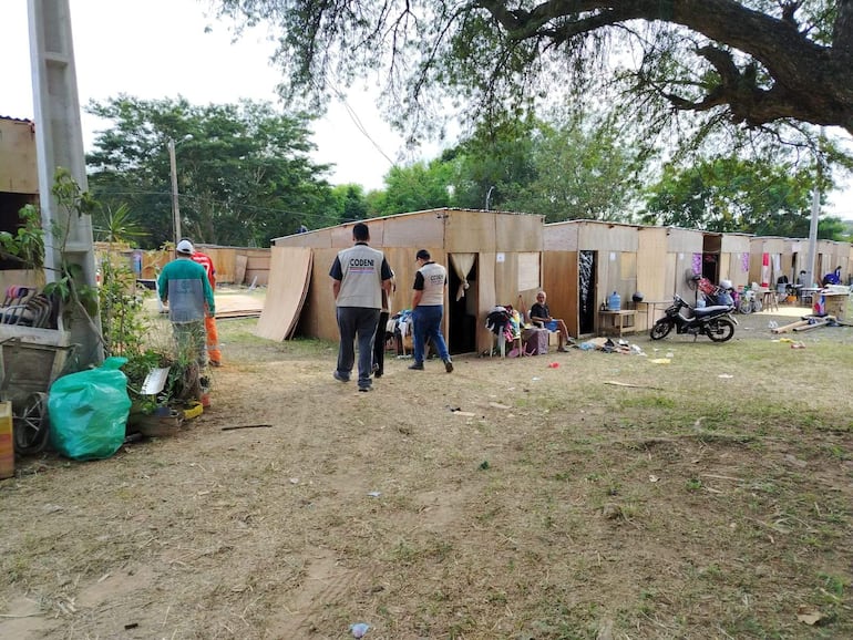 Hombre con chaleco claro de CODEN camina al frente, mientras dos hombres más avanzan y una mujer observa sentada en una silla.