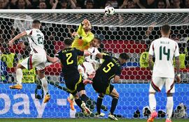 TOPSHOT - Hungary's forward #19 Barnabas Varga falls (C) on the pitch as Scotland's goalkeeper #01 Angus Gunn (up) punches out the ball during the UEFA Euro 2024 Group A football match between Scotland and Hungary at the Stuttgart Arena in Stuttgart on June 23, 2024. (Photo by Fabrice COFFRINI / AFP)