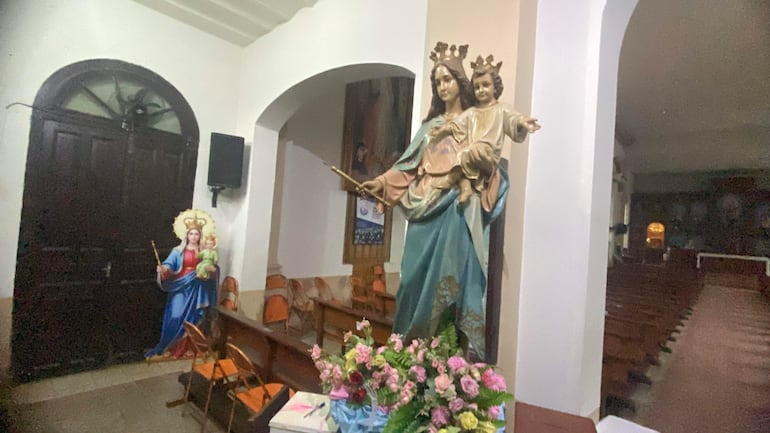 Interior de la iglesia con estatua de la Virgen María y decoración religiosa, en un ambiente tranquilo y luminoso.