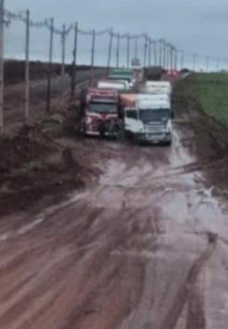 Camiones atascados en un camino de barro bajo un cielo nublado, sin personas presentes en la escena.