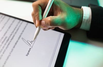 Primer plano de la mano de un empresario firmando electrónicamente en una tableta con un lápiz óptico.