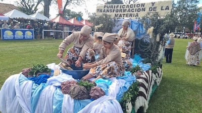 Cinco mujeres en atuendos tradicionales trabajan en un bol grande, rodeadas de telas de colores y un cartel sobre transformación de materia.