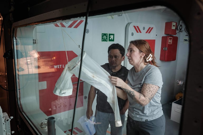 Esta foto, tomada el 9 de enero de 2026, muestra a Larissa Fruehe (derecha), científica alemana especializada en ADN ambiental (eDNA), conversando sobre métodos para filtrar plancton a partir de muestras de agua de mar con un científico marino indonesio a bordo del OceanXplorer, un buque de investigación operado por la organización marina sin fines de lucro OceanX, en aguas frente a la isla de Célebes (Sulawesi).