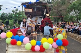 Cinco participantes del desfile en ropa tradicional con globos de colores y una audiencia de fondo, celebrando la primavera.