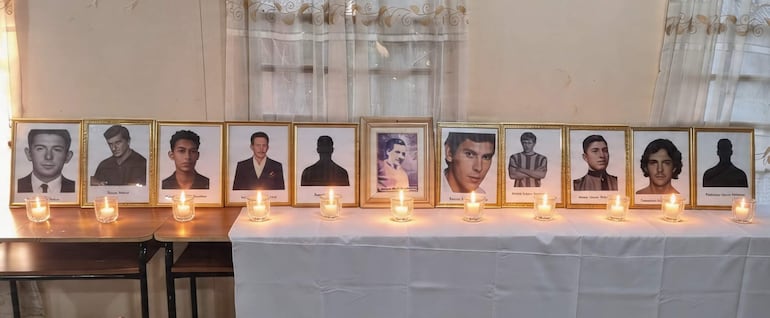 Retratos enmarcados sobre mesa con mantel blanco, rodeados de velas encendidas, creando un ambiente de homenaje y respeto.