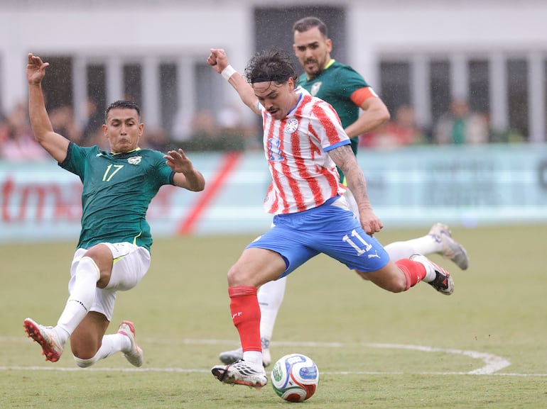 El volante ofensivo de Paraguay, Maurício Magalhães Prado se perfila para disparar ante el intento de cobertura del defensor de Bolivia, Roberto Fernández. (Foto: @Albirroja)