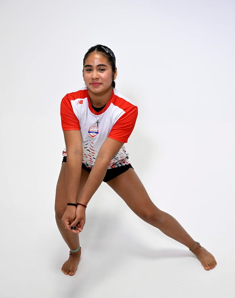Sofía Martínez con camiseta blanca y detalles rojos, en pose dinámica, destacando su actitud atlética con pulseras y diadema en el cabello.