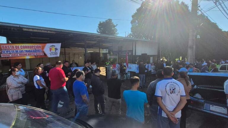 Grupo de docentes con carteles contra la corrupción, algunos escuchan al orador que se dirige a ellos con micrófono en mano.