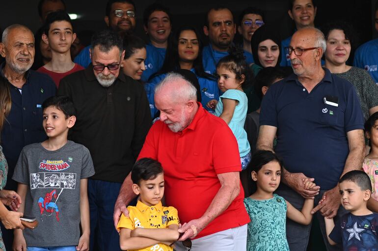 El presidente de Brasil, Luiz Inácio Lula da Silva (c), saluda a personas repatriadas de la Franja de Gaza en un almuerzo, en la Base Aérea Militar de Brasilia (Brasil). Lula da Silva visitó este lunes a un grupo de brasileños y parientes palestinos repatriados el pasado sábado desde la Franja de Gaza y les garantizó apoyo hasta que estén instalados en el país suramericano. EFE/Andre Borges