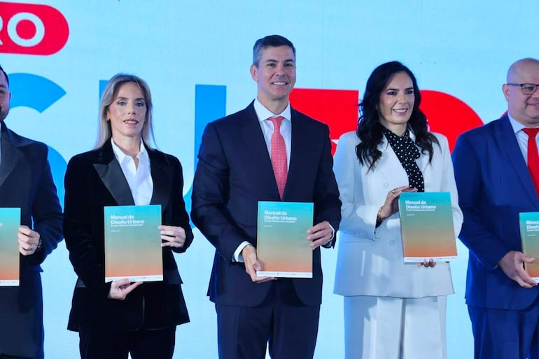 Cinco personas sonriendo, vestidas de formal, sosteniendo el Manual de Diseño Urbano en un ambiente institucional con pantalla de fondo.