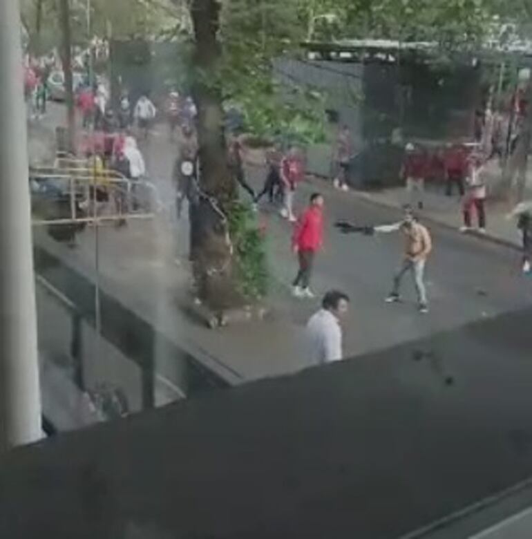 El barrabrava con el torso desnudo alienta a sus demás compañeros  para seguir peleando.