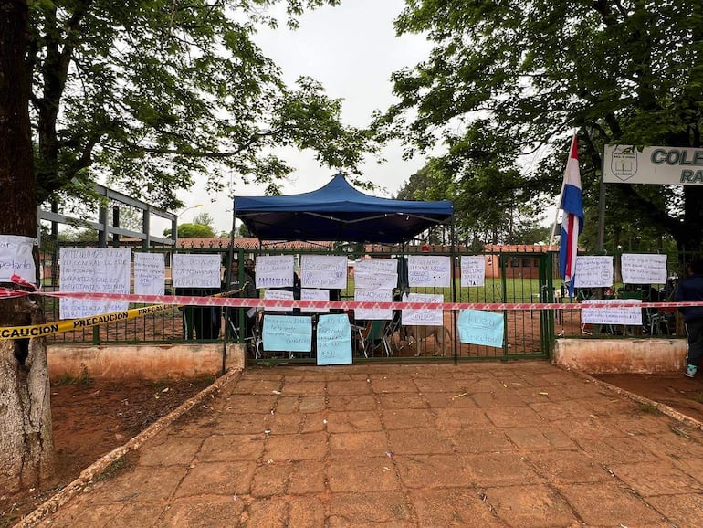 Carteles de protesta en la reja del Colegio Nacional Raúl Arsenio Oviedo, con mensajes claros desde un ambiente exterior.