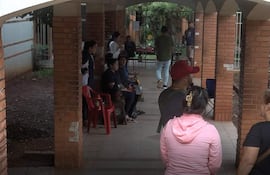 Nueve personas en pasillo del Hospital de Clínicas, algunas sentadas y otras de pie, conversando en un ambiente relajado.