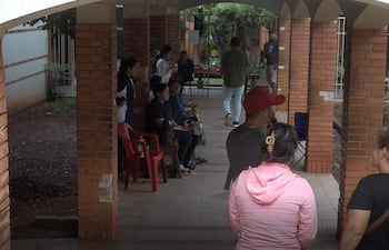Nueve personas en pasillo del Hospital de Clínicas, algunas sentadas y otras de pie, conversando en un ambiente relajado.