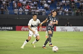 El mediocampista de Sportivo San Lorenzo Axel Galeano extiende el pase ante la presencia cercana del volante ofensivo de Olimpia, Rubén Darío Lezcano.