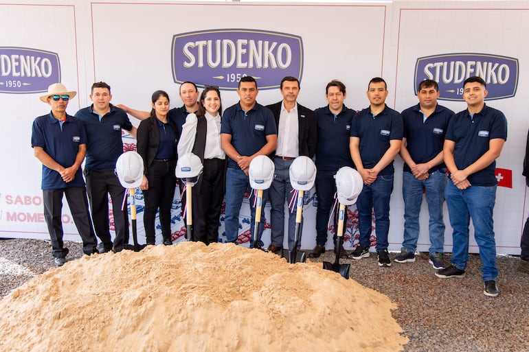 Grupo de 11 trabajadores con camisetas oscuras de STUDENKO, posando junto a palas y una pancarta del evento.