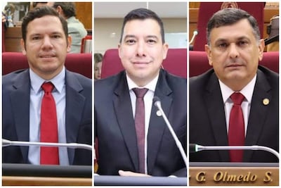 Diego Candia y Edgar Olmedo en trajes formales, con corbatas rojas, en ambiente sobrio de salón de sesiones.