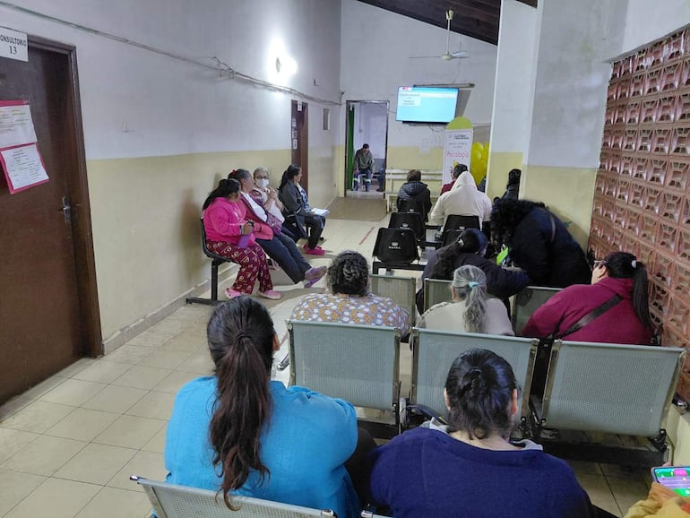 Mujeres de diversas edades esperan en sillas metálicas en un consultorio del hospital, mostrando preocupación por la falta de medicamentos.