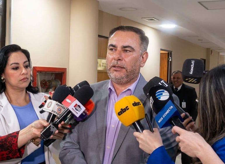 Ever Villalba en traje gris y camisa morada, conversando con dos mujeres periodistas en un entorno de interior.