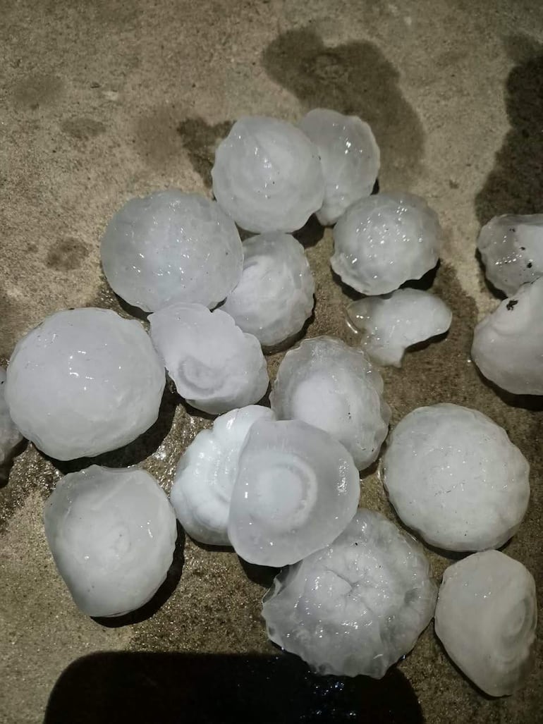 Fragmentos de granizo en superficie de cemento, mostrando diferentes tamaños y texturas tras el temporal.