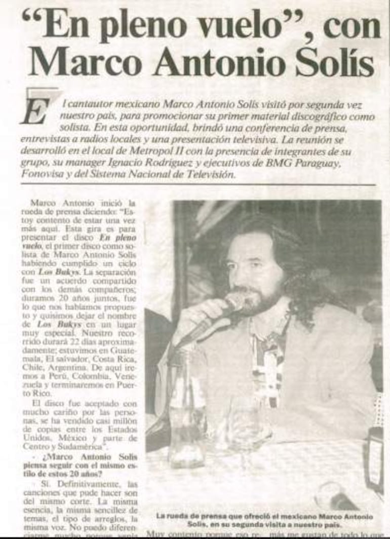 Marco Antonio Solís, con cabello largo y barba, habla en micrófono en Metropol II, rodeado de su equipo y ejecutivos.