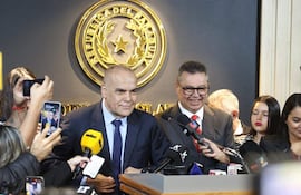 Basilio Núñez con traje oscuro y corbata clara, junto a Gustavo Leite en traje claro y corbata roja, en rueda de prensa oficial.