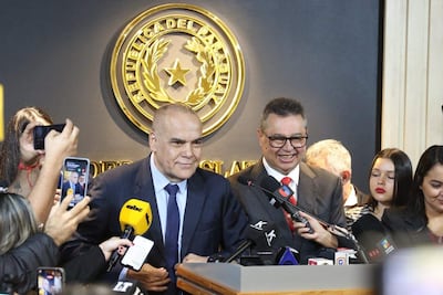 Basilio Núñez con traje oscuro y corbata clara, junto a Gustavo Leite en traje claro y corbata roja, en rueda de prensa oficial.