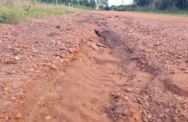 Camino rural deteriorado con hendidura central, rodeado de hierba y arbustos en zona de San Cristóbal.