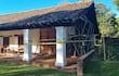 Construcción rústica del museo Jesuítico rodeada de cintas de precaución, con columnas blancas y vegetación verde alrededor.