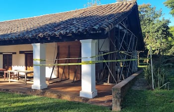 Construcción rústica del museo Jesuítico rodeada de cintas de precaución, con columnas blancas y vegetación verde alrededor.