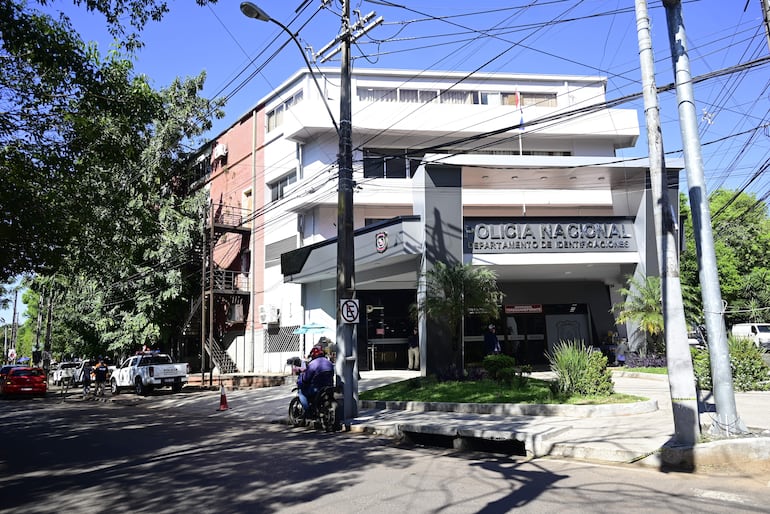 Fachada del edificio de la Policía Nacional, con vehículos policiales y un día despejado.