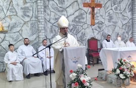 Monseñor Omar López, con mitra y capa blanca, habla frente a un micrófono, rodeado de clérigos y un altar decorado.