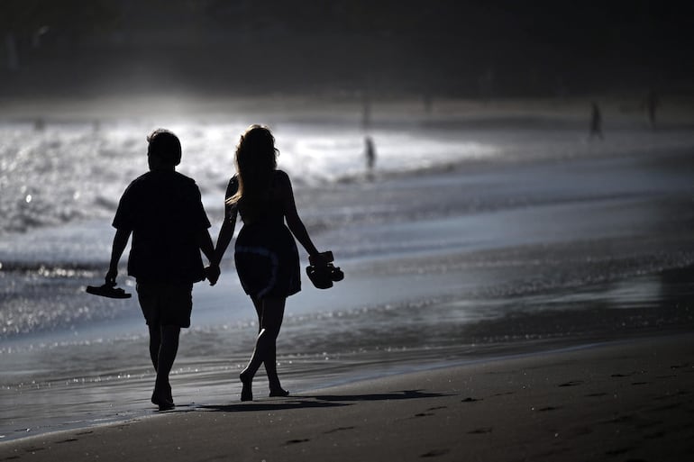 Una pareja camina por la orilla del mar en la playa El Tunco, en La Libertad, El Salvador, el 13 de febrero de 2026.
