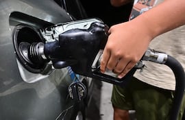 Un hombre carga combustible a un vehículo en una estación de servicio.