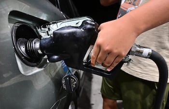 Un hombre carga combustible a un vehículo en una estación de servicio.
