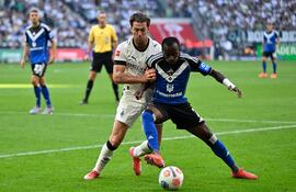 Joe Scally (i), defensor del Mönchengladbach, disputa el balón con Mamadou Diarra, delantero del Hamburgo SV, durante el partido disputado hoy. (AFP).
