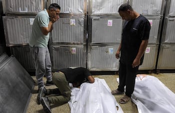 Unos hombres lloran junto al cuerpo de una de las varias víctimas mortales tras el bombardeo israelí contra una comisaría de policía en el campamento de refugiados palestinos de Jabalia, en el norte de la Franja de Gaza, antes de su funeral en la morgue del hospital Al-Shifa de la ciudad de Gaza, el 14 de julio de 2026.