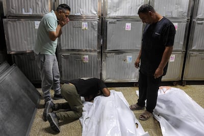 Unos hombres lloran junto al cuerpo de una de las varias víctimas mortales tras el bombardeo israelí contra una comisaría de policía en el campamento de refugiados palestinos de Jabalia, en el norte de la Franja de Gaza, antes de su funeral en la morgue del hospital Al-Shifa de la ciudad de Gaza, el 14 de julio de 2026.