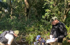 El cuerpo del terrorista Rubén Darío López Fernández, alias Loro, en el suelo junto a un fusil. Aparecen también el forense Gabriel Rotela (camisa blanca), un policía de Criminalística (quepis azul) y el fiscal Lorenzo Lezcano (parado).
