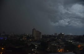 Paisaje urbano de Asunción bajo cielos densamente nublados, edificios iluminados en la parte inferior, sin personas visibles.