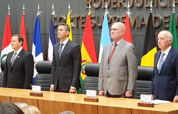Alberto Martínez Simón, Emiliano Rolón Fernández, y César Diesel en formalidad, serios, con banderas tras ellos en ambiente institucional.