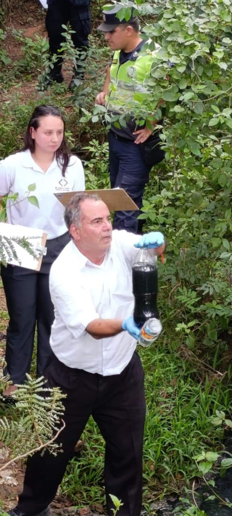 El técnico industrial del Ministerio Público, César Mortello, traslada muestra de agua captada del arroyo Piro’y en Pirayú.
