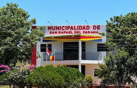 Edificio de la Municipalidad de San Rafael del Paraná, con banderas y un cielo despejado rodeado de vegetación.