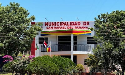 Edificio de la Municipalidad de San Rafael del Paraná, con banderas y un cielo despejado rodeado de vegetación.